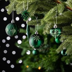 green christmas ornaments hanging from the branches of a tree with white and black polka dots in the background