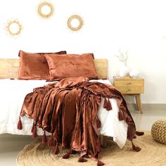 a bed covered in brown and white sheets with tassels on the pillow cases