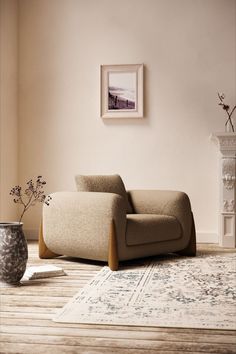 a living room with a chair, rug and vase on the floor in front of it