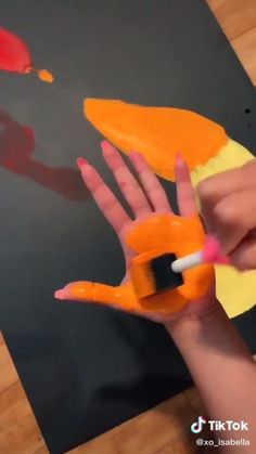 a person is holding up a fake hand with paint on it and the fingers are painted orange