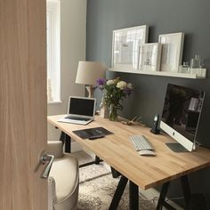 a laptop computer sitting on top of a wooden desk next to a lamp and window