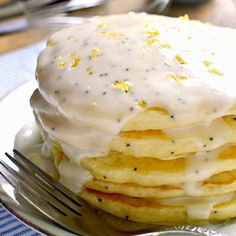 a stack of pancakes covered in white frosting and sprinkled with lemon zest