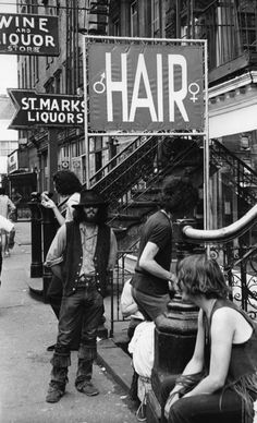 a group of people standing on the side of a street next to a sign that says hair