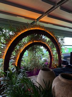 an outdoor garden area with potted plants and large archways in the center, surrounded by greenery