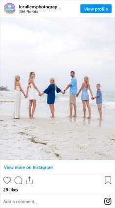 a group of people standing on top of a beach holding hands