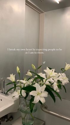 a vase filled with white flowers sitting on top of a sink