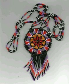 a beaded necklace with an orange, black and red design on the front hanging