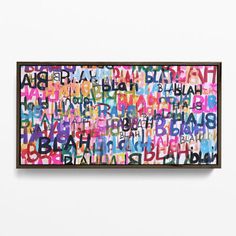 an art piece hanging on the wall with words written in different colors and sizes, including letters