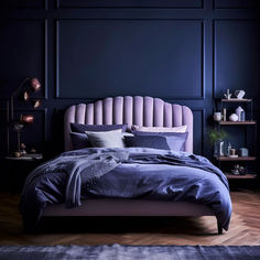 a bed with blue sheets and pillows in a dark colored room, next to a book shelf