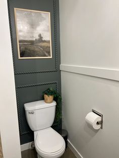 a white toilet sitting in a bathroom next to a painting on the wall above it