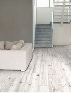 a white couch sitting in front of a stair case on top of a hard wood floor