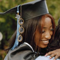 a woman in graduation cap and gown hugging another woman's shoulder while she is wearing a tassel