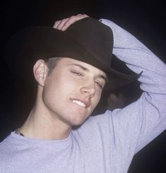 a young man wearing a black cowboy hat