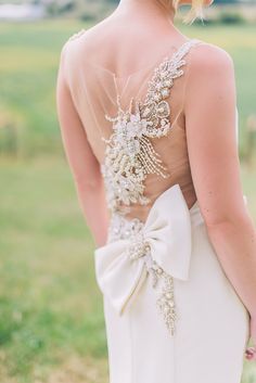 the back of a bride's wedding dress with a large bow at the waist