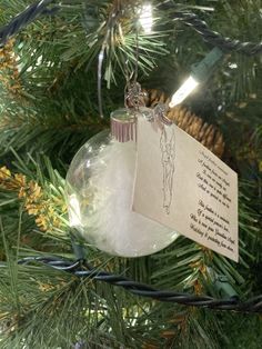 a christmas ornament hanging from a tree with a note attached to the top