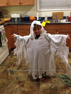 a child in a ghost costume standing on the kitchen floor