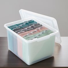 a plastic container filled with files on top of a wooden table