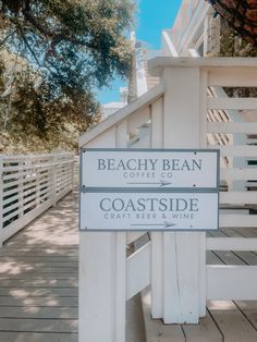 a sign that is on the side of a wooden walkway next to a white fence