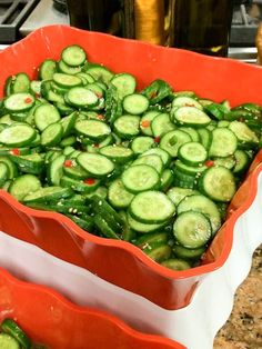 two red bowls filled with sliced cucumbers on top of a counter