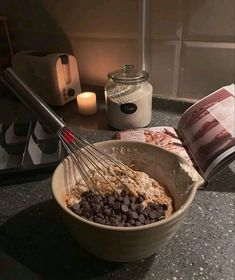 a mixing bowl filled with chocolate chips and oatmeal next to a candle