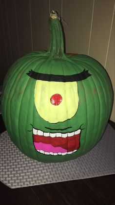 a large green pumpkin with a face painted on it