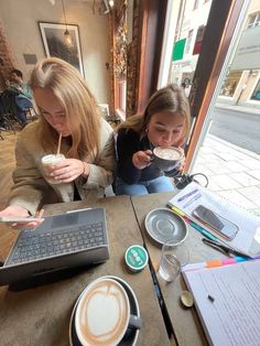 two women sitting at a table with cups of coffee