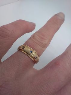 a person's hand wearing a gold ring with blue sapphire stones on the side