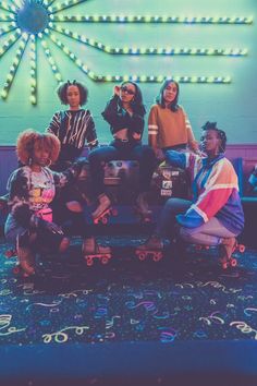 group of people sitting on top of a skateboard in front of a neon sign