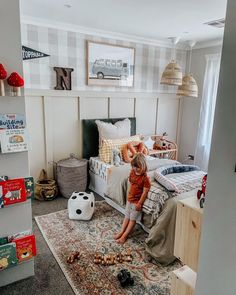 a young boy sitting on top of a bed in a bedroom next to a soccer ball