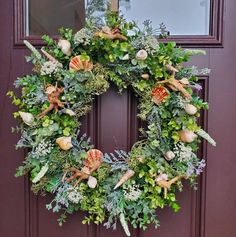 a wreath with shells and greenery is hanging on the front door's purple door