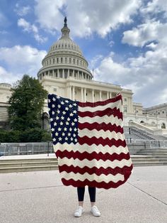 a person standing in front of the u s capitol building holding an american flag blanket