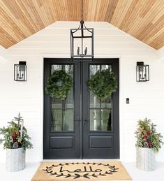 a black double door with two wreaths on the top and one hanging above it