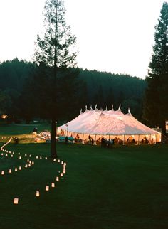 a large tent set up with candles in the grass