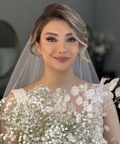 a woman in a wedding dress holding a bouquet of flowers and smiling at the camera