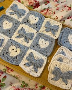 a crocheted baby blanket with blue and white bows on it next to two matching diapers