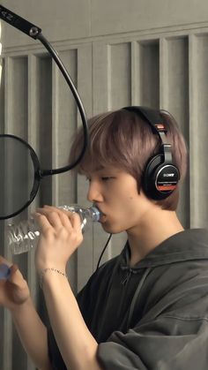 a young man wearing headphones drinking from a water bottle