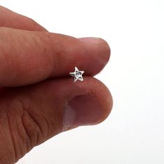 a person's hand holding a tiny star shaped ring