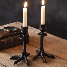 two candles are sitting next to each other on a wooden table with an old book in the background