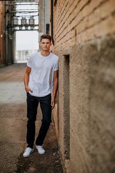 a young man leaning against a brick wall