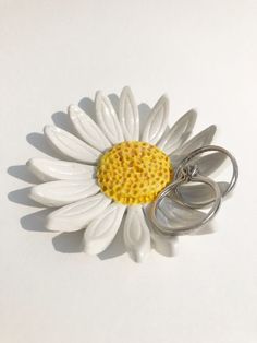 a white and yellow flower with two pairs of silver rings on the bottom of it