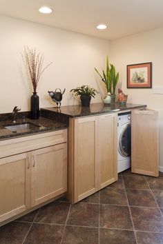 a washer and dryer in a room with wood cabinets, marble counter tops and tile flooring