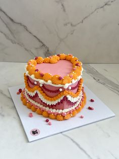 a heart shaped cake sitting on top of a white countertop next to a marble wall