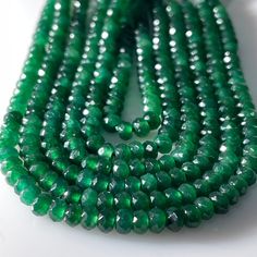 green glass beads are arranged on a white surface