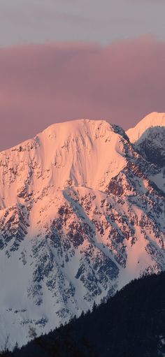 the mountains are covered in snow at sunset