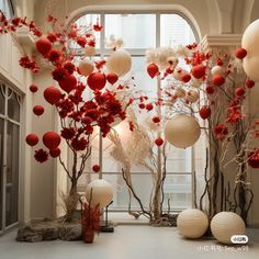 the room is decorated with red and white flowers, paper lanterns and branches in vases