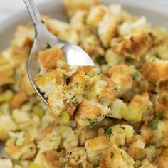 a close up of a spoon in a bowl of food with stuffing and vegetables on it