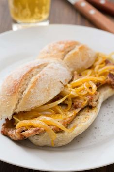 a sandwich with cheese and meat is on a plate next to a glass of beer