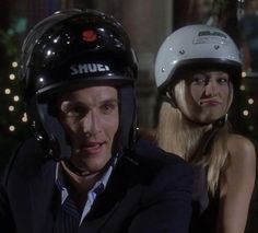 a man in a suit and helmet sitting next to a woman