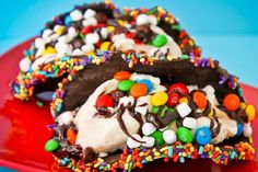 two pieces of chocolate covered ice cream with sprinkles and m & ms