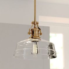 a clear glass light fixture hanging from a ceiling in a room with white walls and windows